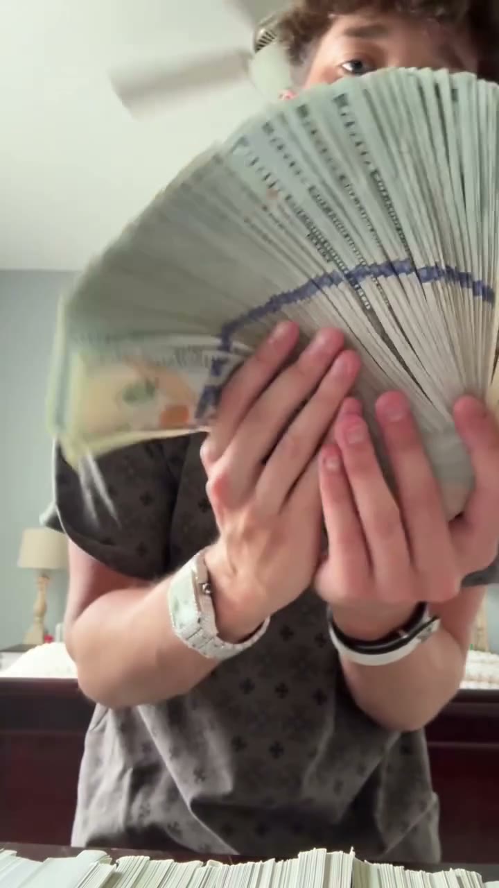 The completed fan of notes rises across the performer’s lower face in the final Money Spread pose.